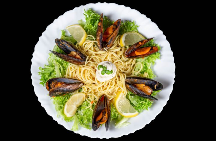 Spaghetti With Mussels And Lettuce On A White Plate