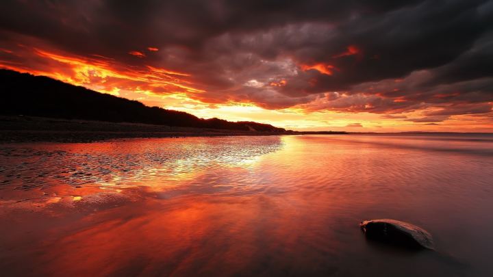 Nature Stone In Shallow Water On A Background Of Red Sunset