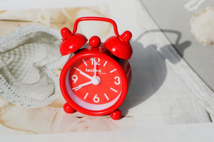 Small Red Alarm Clock Stands On The Table