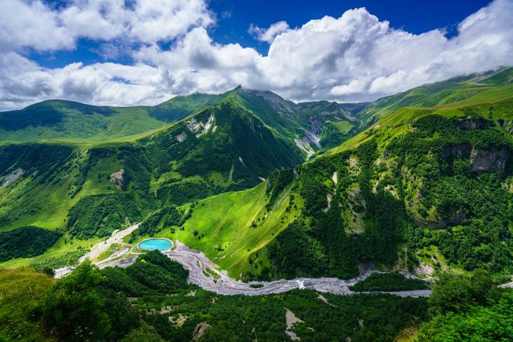 Beautiful Scenic Green Hills Under A Blue Sky With White Clouds